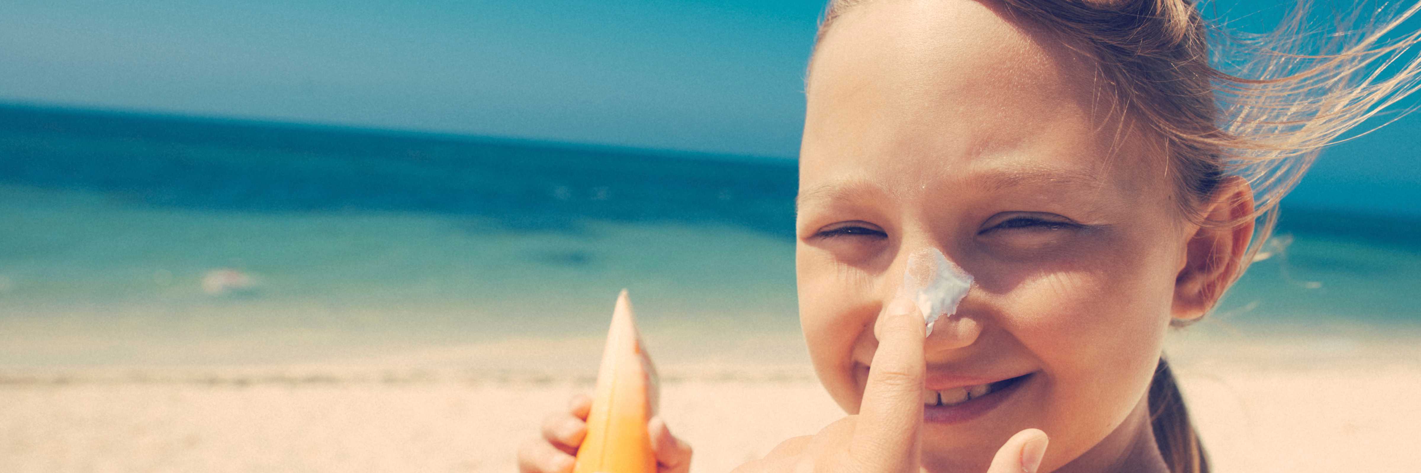 Girl applying sunscreen to her nose.